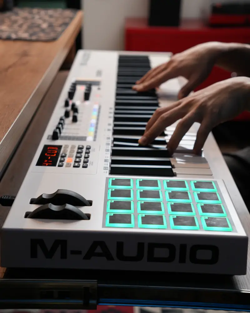 Руки на MIDI-клавиатуре M-Audio с подсвеченными пэдами